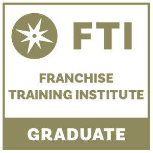 a square badge with gold typography displaying the words: FTI Franchise Training Institute Graduate.
