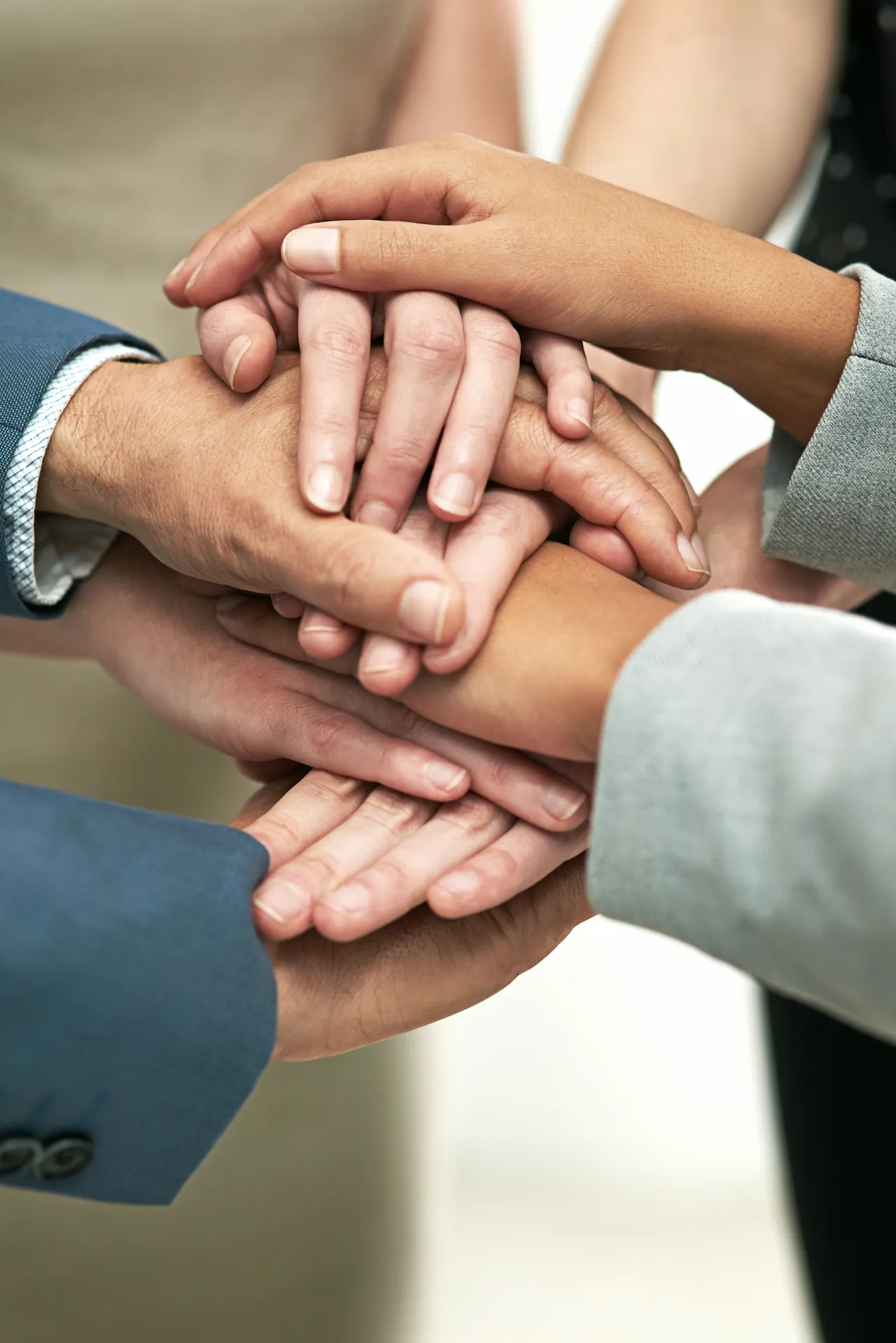 group of business people stacking their hands on one another in team huddle